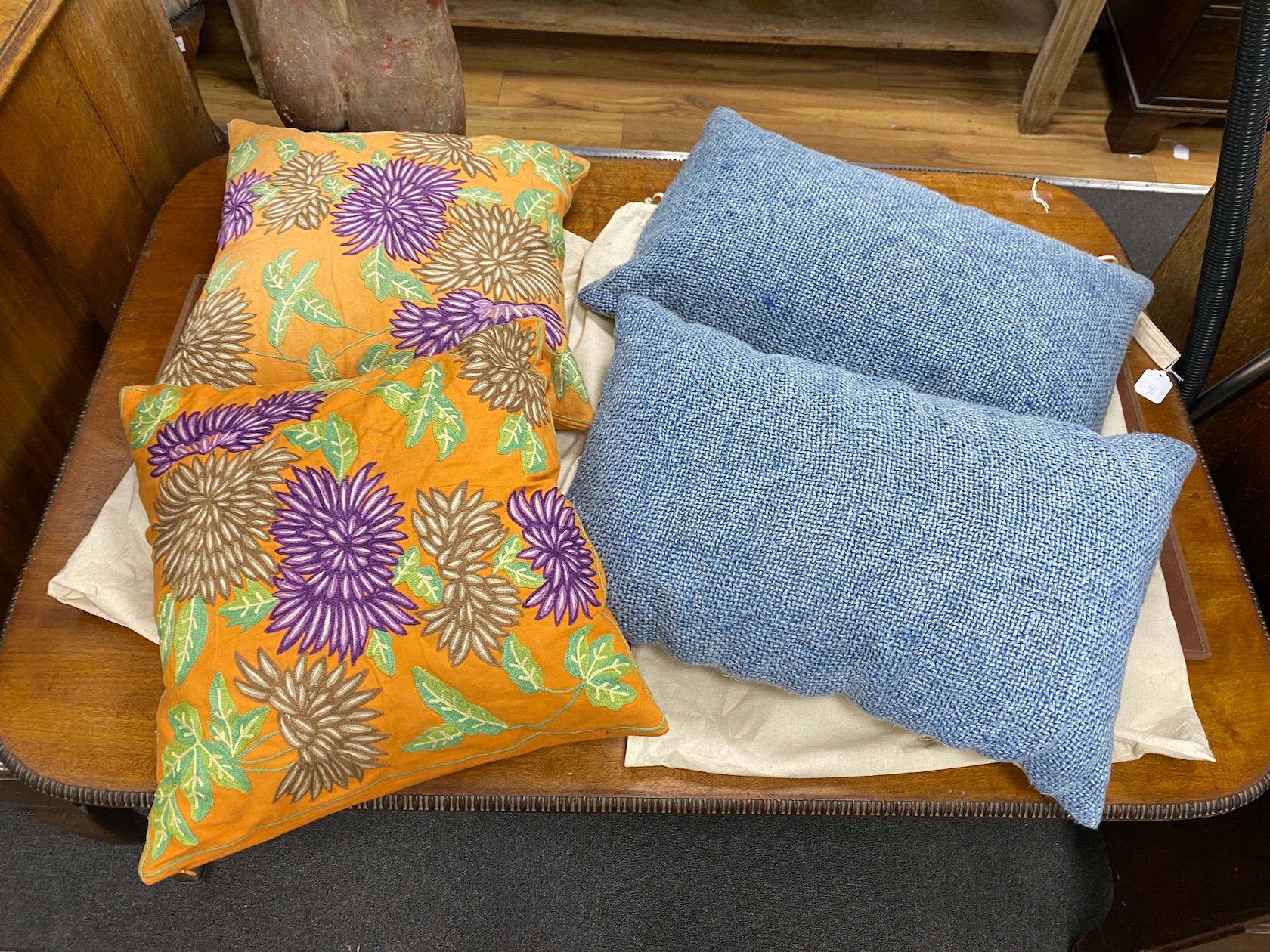 Two pairs of polychrome floral embroidered and blue woven cushions, larger 50cm square.